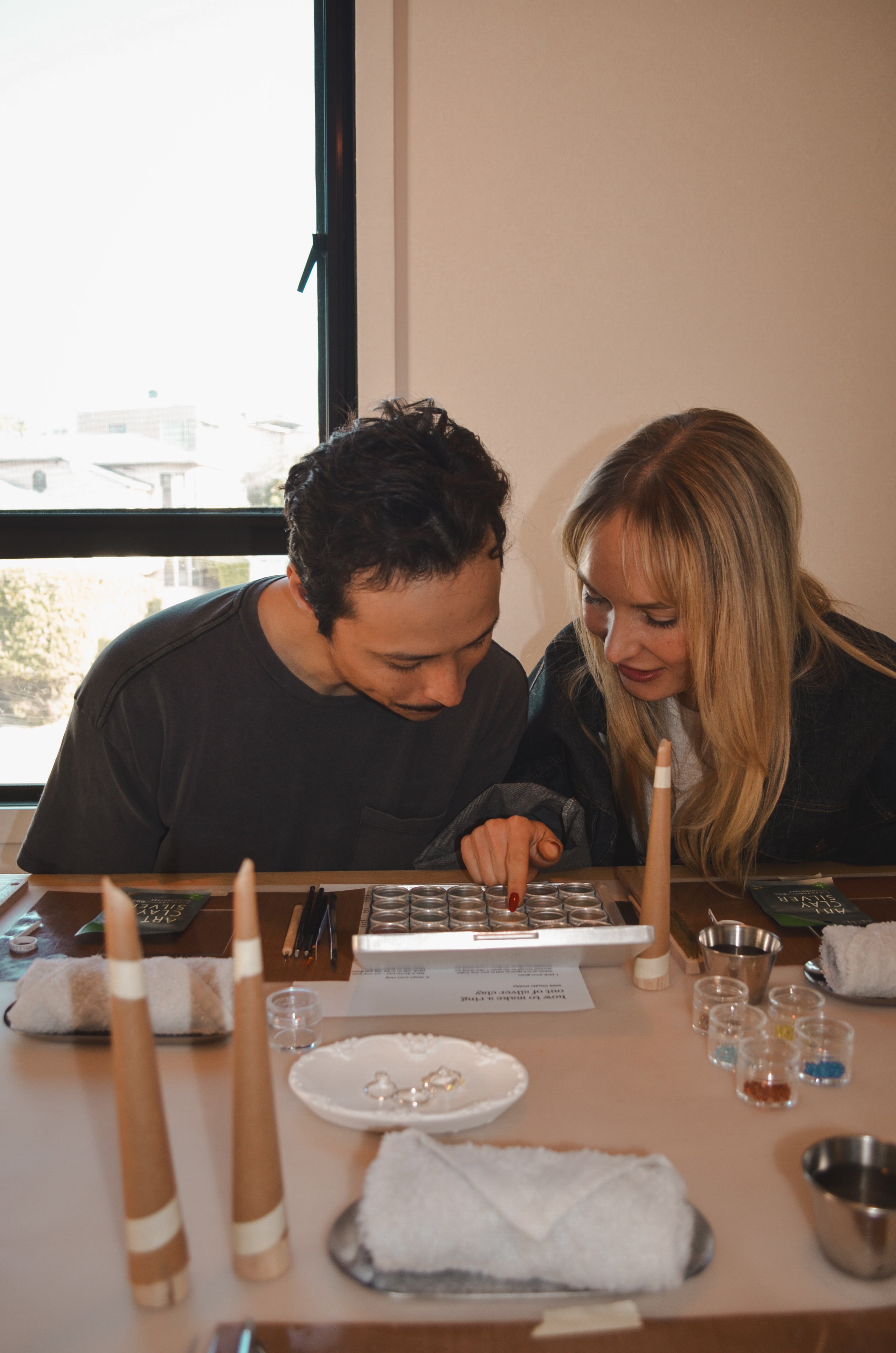 Two people sitting at a table with various tools, looking at gems.