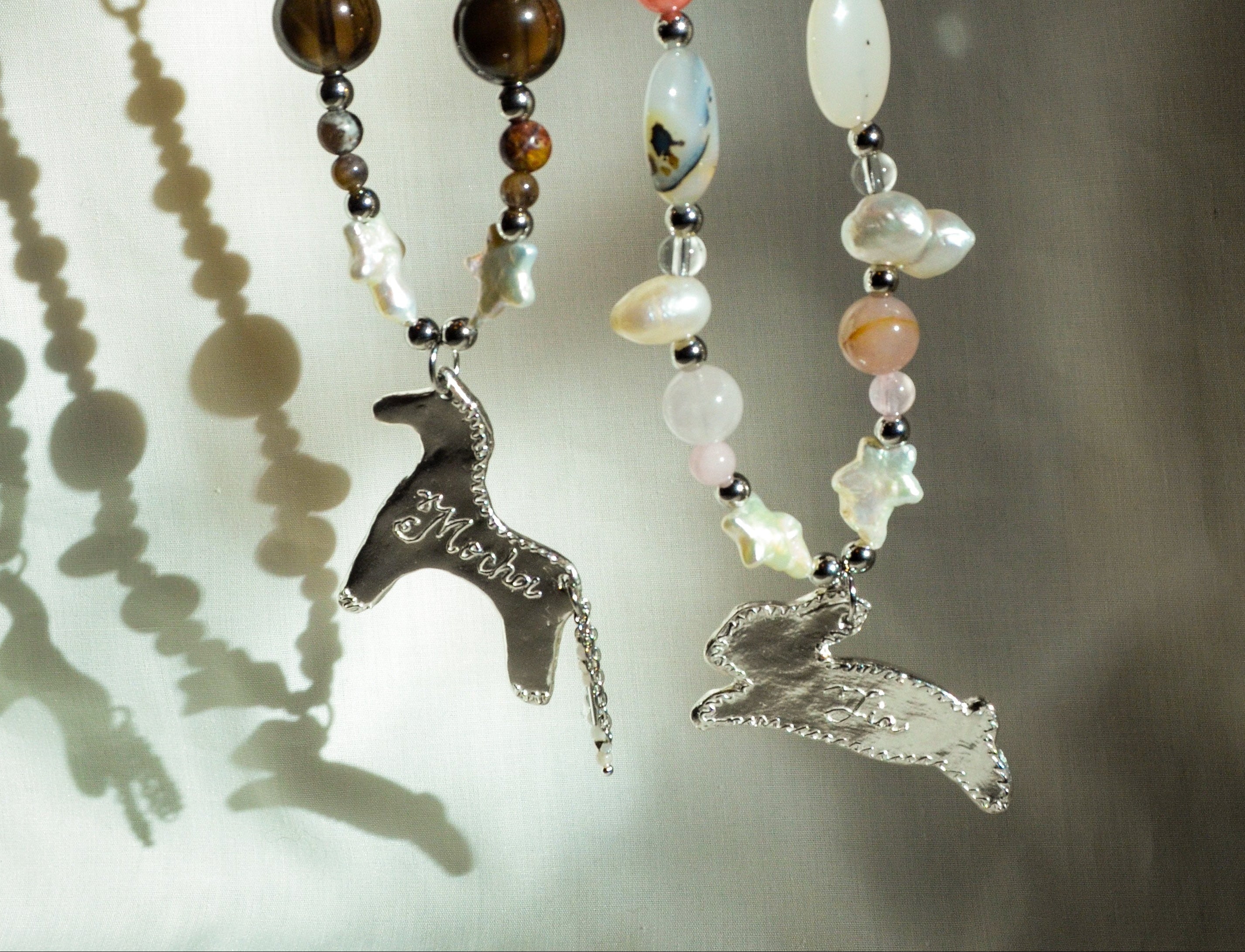 Necklaces with animal pendants and beads on a neutral background