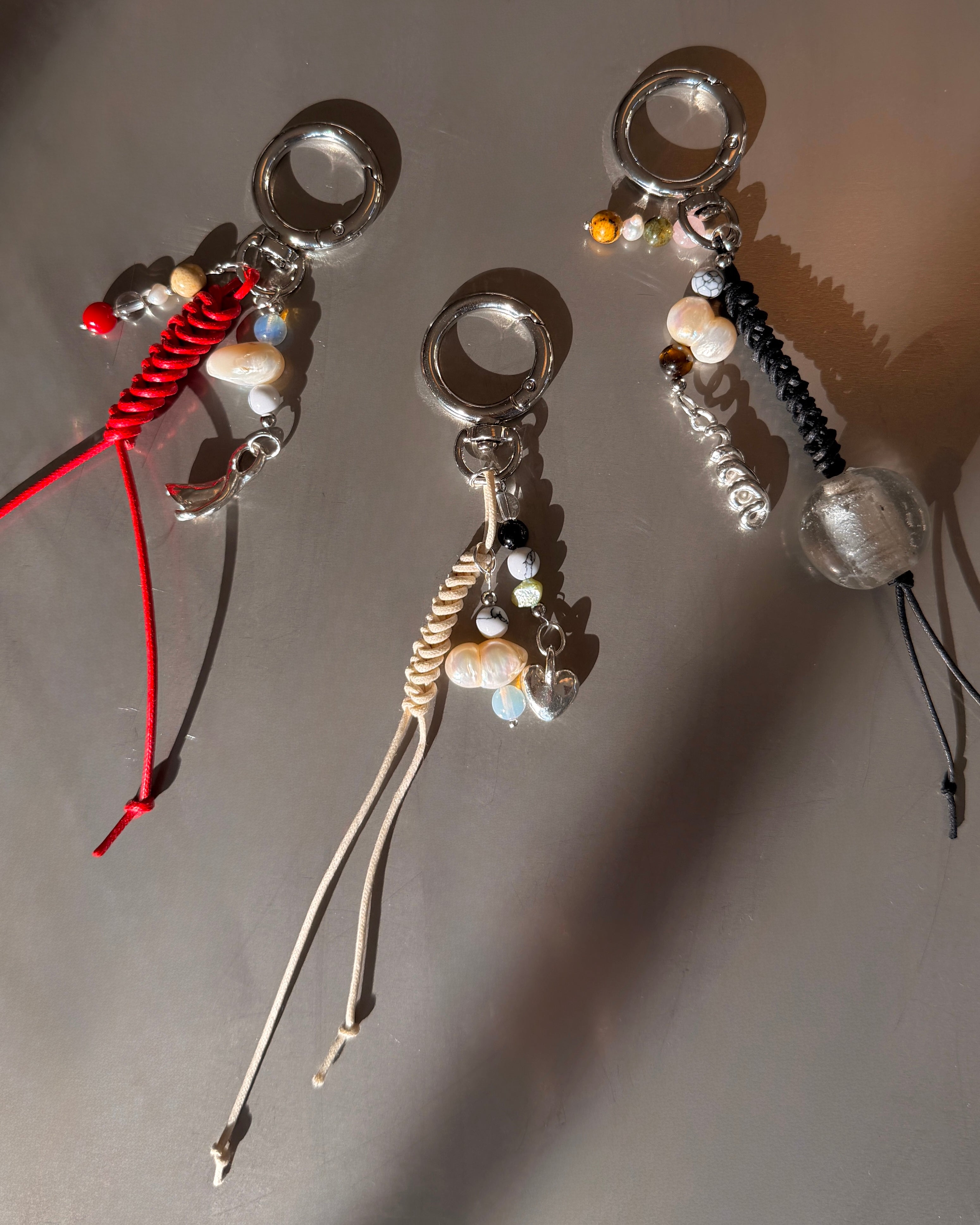 Three decorative keychains with beads and strings on a gray background