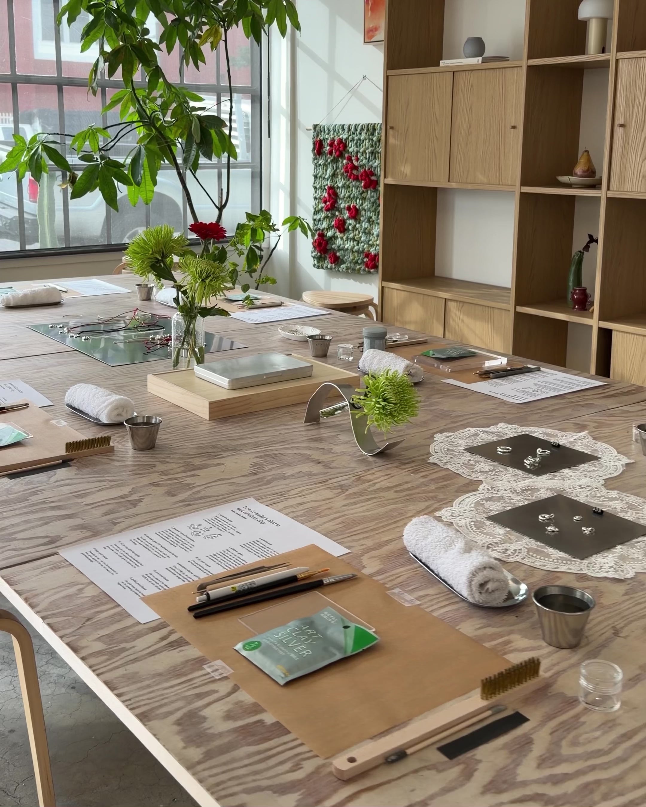 Room with a long table set for crafting silver clay rings.